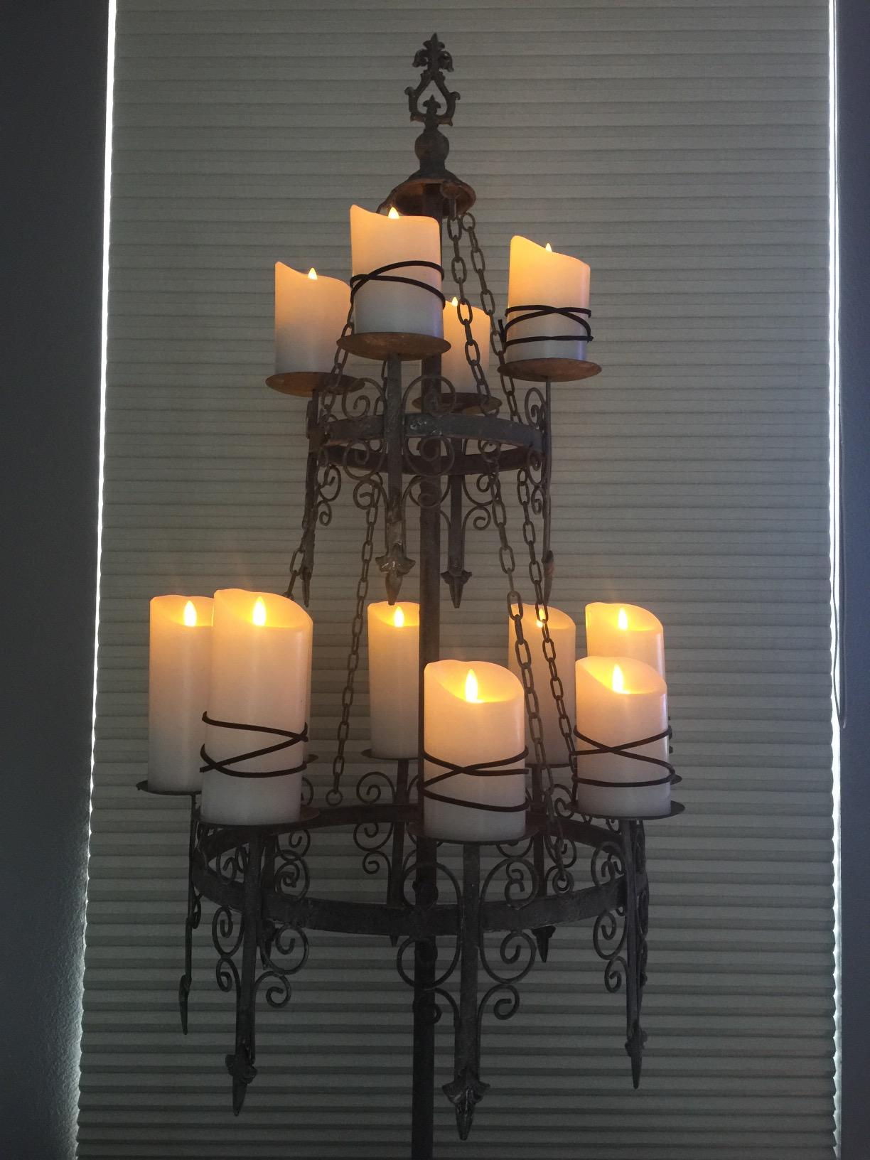 black candelabra metal chandelier warm LEDcandles closeup window blinds medieval candle holder