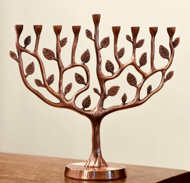 brown tree branches leaves closeup white wall blurry menorah candle holders